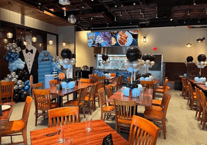 Restaurant dining room decorated with black, silver, and blue balloons for a "Boss Baby" themed event.